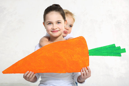 Brother and sister posing with painted carrotの写真素材