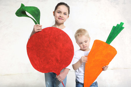Brother and sister posing with painted carrot and beet in studioの写真素材