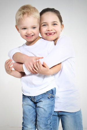 Brother and sister hugging isolated on whiteの写真素材