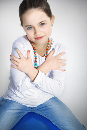 Portrait of cute girl sitting on a blue ball, closeupの写真素材