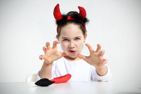 Portrait of little girl dressed as pretty imp showing a tongueの写真素材
