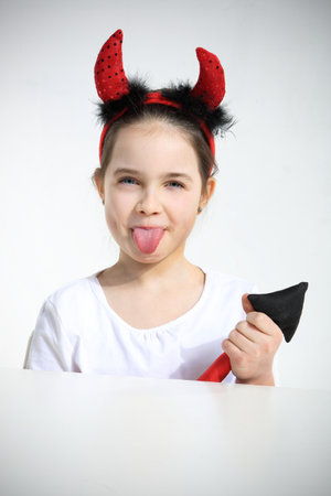 Portrait of little girl dressed as pretty imp showing a tongueの写真素材