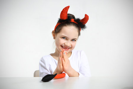 Cute little girl in imp suit on whiteの写真素材