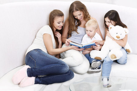  Three girls and a boy sitting on the sofaの写真素材