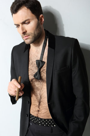 Sexy male model smoking cigar in open formal attireの写真素材