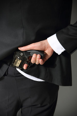 A man conceals a firearm in the back of his pants の写真素材