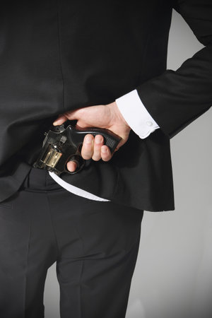 A man conceals a firearm in the back of his pants の写真素材