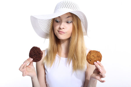 Cute young woman eats cookies on the white backgroundの写真素材