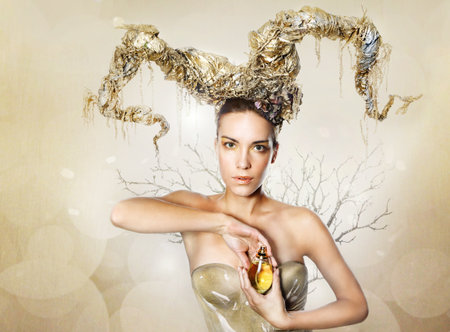 woman with golden horns is holding a perfume bottleの写真素材