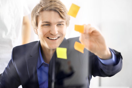 Young, handsome man of success in the office room glued yellow notes の写真素材