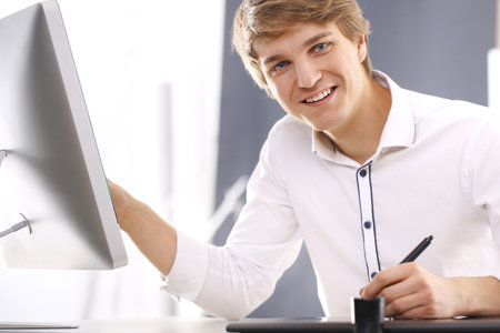 Happy young worker with computerの写真素材