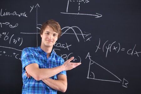 Young happy student on the background of the table recorded mathematical formulas の写真素材