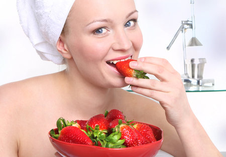 Fruit diet  Attractive girl with a bowl of ripe strawberries relaxes in the living room  の写真素材