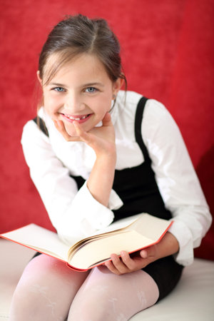 Joyful girl reading a book sitting on the chair