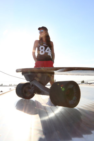 Skateboarding, fashion and style .Young girl on the roof relaxes in the rays of the setting sun.の写真素材