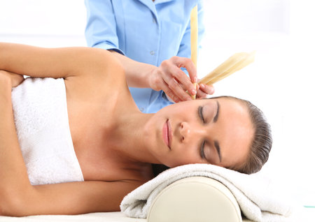 Woman relaxes in the study of natural medicine ear candling treatment.の写真素材