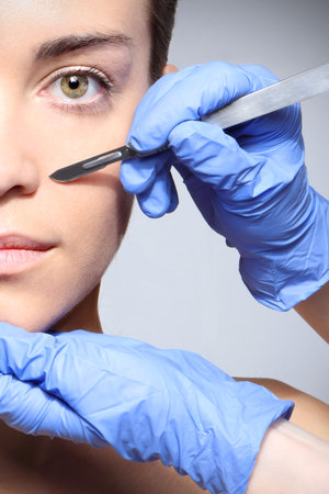 Caucasian woman during surgery using a scalpelの写真素材