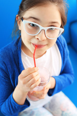 Healthy fruit cocktail. Girl drinking milk cocktail through a strawの写真素材