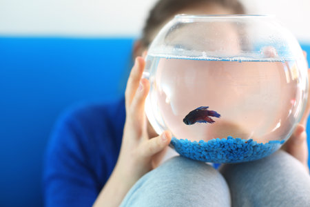 Blue fish. Child holding a crystal ball with blue a fishの写真素材