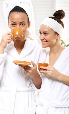 Two women in wellness salon dressed in white robesの写真素材