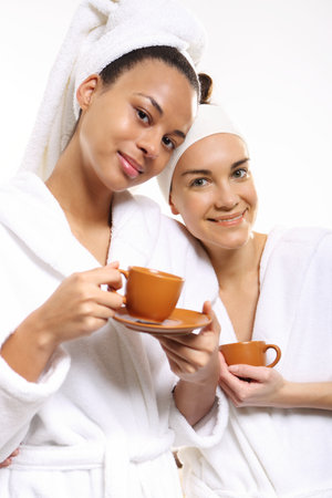 Two women in wellness salon dressed in white robesの写真素材