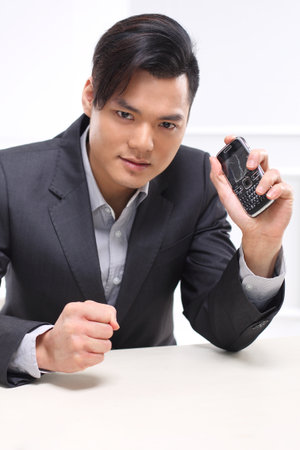 Handsome man in a suit destroys the phone and punches in a deskの写真素材
