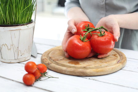 Tomato woman preparing a meal. Hands woman standing in the kitchen while chopping tomatoesの写真素材
