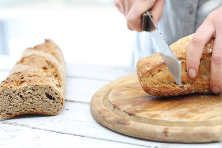 Woman hands cutting bread on the kitchen counterの写真素材