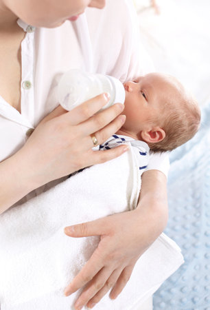 Mother is feeding a newborn baby. A woman feeds a newborn with modified milk from a bottleの写真素材