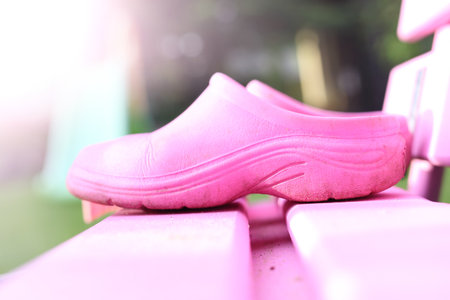 Pink clogs. The composition of pink shoes standing on a pink bench in the sunny gardenの写真素材