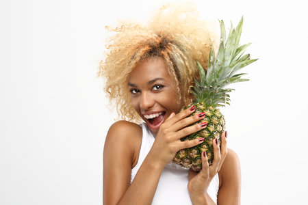Pineapple exotic midfielder in a diet. The dark-skinned cheerful girl holds in her hands the pineappleの写真素材