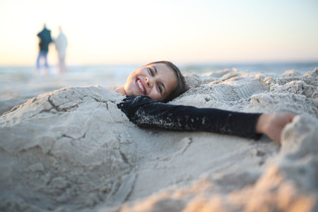 Beach, joy and fun. Laughing, happy girl lying on a sandy beachの写真素材