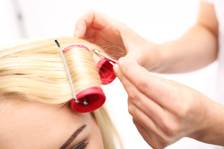 Barber winds shafts, perm. A woman in a hair salon, barber turns hair on rollersの写真素材