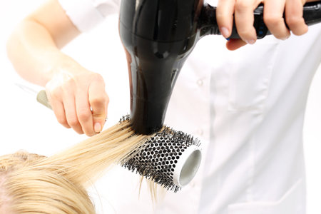 Hairdresser dry hair. The woman at the hairdresser, barber models hair on a round brushの写真素材