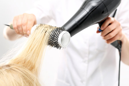 Hair styling brush. The woman at the hairdresser, barber models hair on a round brushの写真素材