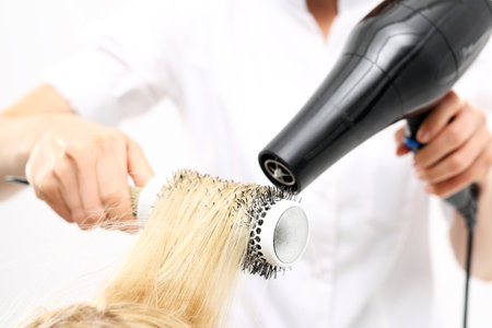Drying hair. The woman at the hairdresser, barber models hair on a round brushの写真素材