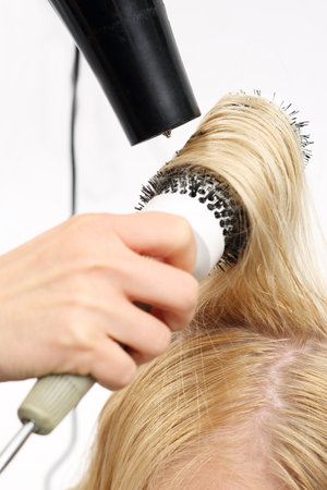 Styling brush. The woman at the hairdresser, barber models hair on a round brushの写真素材