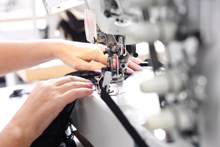 Sewing on a machine. Seamstress sewing on the sewing machine in the manufacturing plantの写真素材