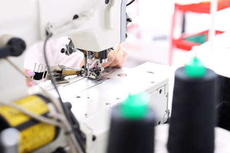 Sewing on a machine. Seamstress sewing on the sewing machine in the manufacturing plantの写真素材