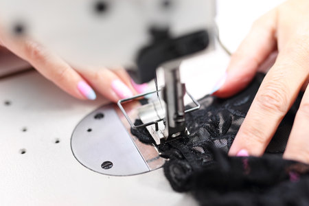 Production of apparel. Seamstress sewing on the sewing machine in the manufacturing plantの写真素材