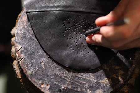Punch leather for shoes. Shoemaker's workshop, append Grinding cast heels shoes in shoe manufacturing plant Work shoemaker, an artist craftsman Punch leather for shoes shoemaker.の写真素材