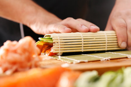 How to prepare sushi. Twisting sushi rolls on a bamboo matの写真素材