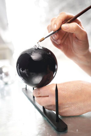 Work on decorating Christmas baubles. A woman painting a design on a baubleの写真素材