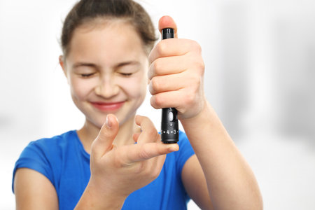 Girl with diabetes is a measure of blood sugar levels using a glucometerの写真素材