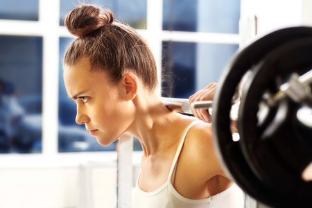 Weight lifting. The woman is picking barbell in gymの写真素材