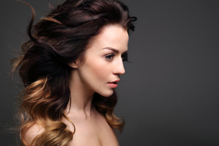 Curls, hair full of volume. Portrait of a beautiful woman on a black background.の写真素材
