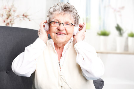 A moment of relaxation, rest grandmother listening to music.の写真素材