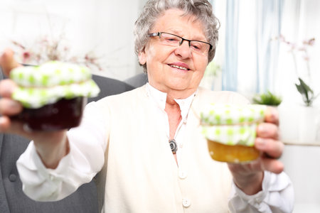 Mature woman with personally prepared jars of jams.の写真素材