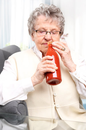 Grandma's preserves, puree with red tomatoes. An elderly woman with a bottle personally prepared processed tomato productsの写真素材