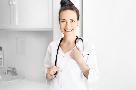 Pediatrician. Young smiling doctor in a white coat with a stethoscope.の写真素材